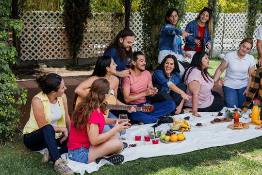 Big latin family sitting on picnic blanket in park during weekend Sunday sunny day in Mexico Latin America. Hispanic diverse and multi generation people in outdoors activities