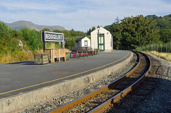 Beddgelert railway station platform on the Welsh Highland Railway in Eryri National Park (Snowdonia), North Wales, showing the station sign, waiting shelter, and curved tracks.