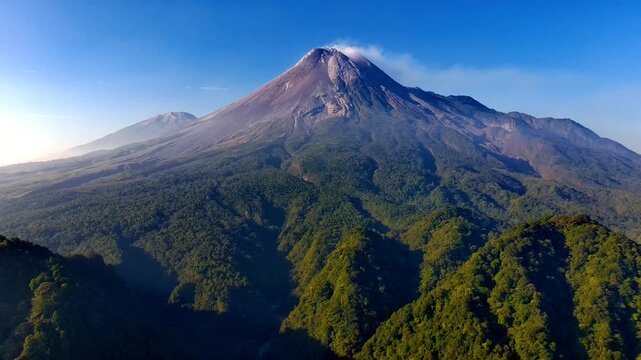 Aerial view of Mount Merapi volcano rising above the lush green forests of Kaliurang in Pakem, Special Region of Yogyakarta, Indonesia.
