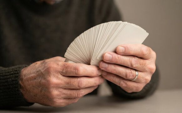 Elderly man holding and fanning a deck of blank white playing cards in hands representing memory games and learning concepts