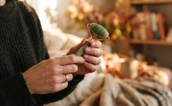 Woman holding a jade face roller for skincare routine at home