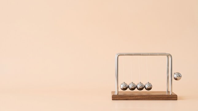 Newton cradle demonstrating physics momentum on a beige background