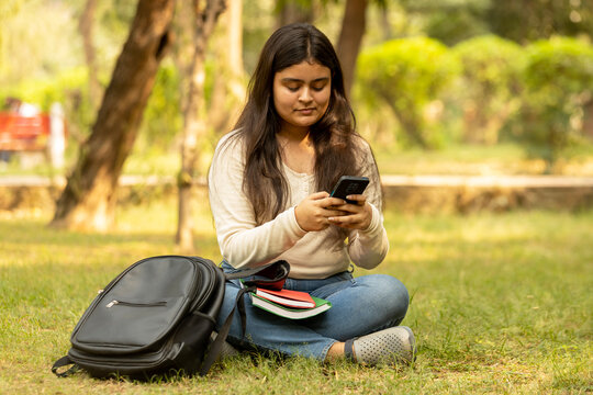 Happy teenager student girl talking on the phone in the park. Concept of Educational girl in india