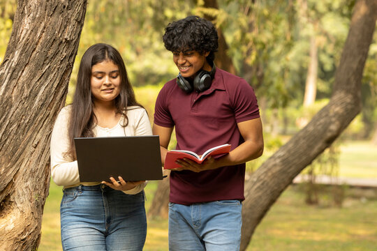 Young Indian college student couple enjoy, talking and reading notebooks while standing in the campus's park together. university lifestyle concept. Student Exams 