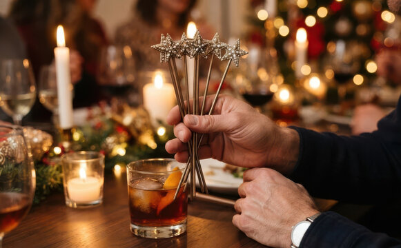 Man holding star cocktail stirrers at a festive Christmas dinner party with candles and drinks
