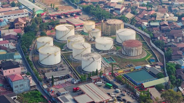 Aerial view of the PT. Pertamina TBBM fuel storage facility with large cylindrical tanks surrounded by dense urban residential buildings in Samarinda, East Kalimantan, Indonesia.
