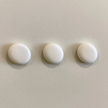Three White Round Objects on Textured Wall