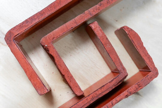 Several handmade red textured brick shaped molds rest on a wooden table, used for decorative wall cladding and diy masonry projects.
