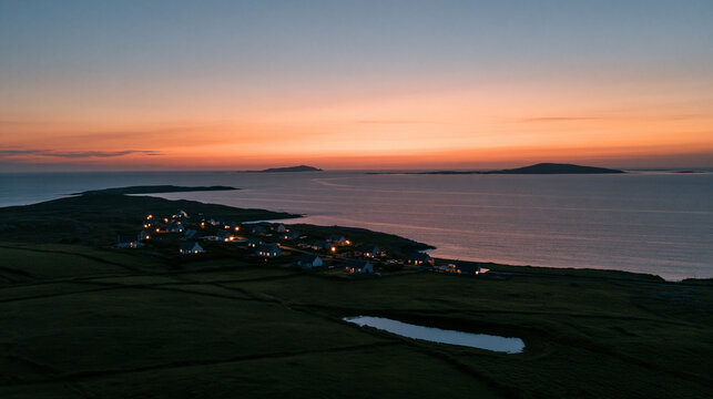 Aerial view of a coastal village at sunset with glowing house lights