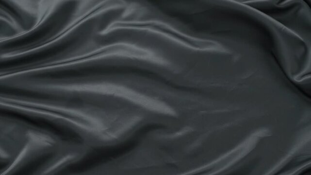 Luxurious dark grey satin or silk fabric texture with soft flowing waves and folds