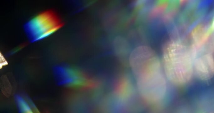 Light ray shining through a prism for beams of sparkling lights, shimmering bokeh, and a brilliant dazzling rainbow of lens flares. Visual effect of a light burst through swirling reflective glass.