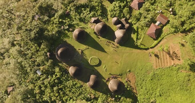 Aerial view of Waerebo Village with traditional conical houses surrounded by lush green mountains and forest in Satar Mese Barat, East Nusa Tenggara, Indonesia.