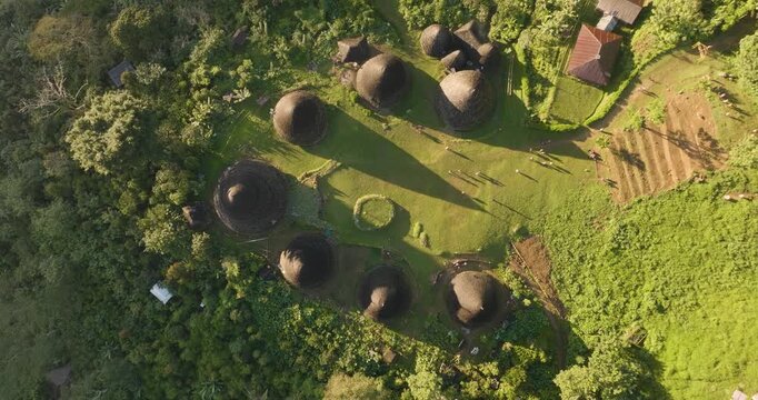 Aerial view of the traditional conical houses of Waerebo Village surrounded by lush green mountains in Satar Mese Barat, East Nusa Tenggara, Indonesia.
