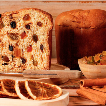 Traditional panettone in a Christmas setting, sliced to reveal candied fruit and raisins with a soft texture.