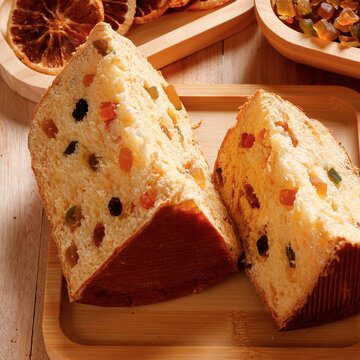 Traditional Christmas panettone with candied fruit and raisins, sliced, on a rustic festive table.