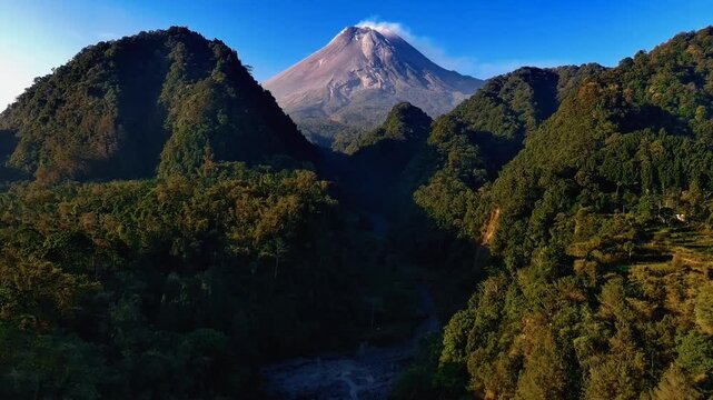 Aerial view of Nawang Jagad and the volcanic landscape of Mount Merapi surrounded by lush green forests in Kecamatan Pakem, Daerah Istimewa Yogya, Indonesia.