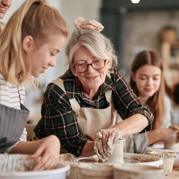Mature woman in plaid shirt teaching pottery technique to children