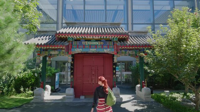 Female traveler walking through a dark traditional Chinese doorway into a sunny courtyard, exploring Asian architecture