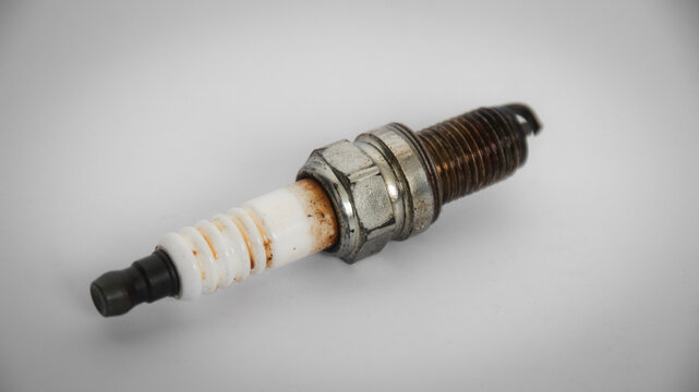 A used spark plug with visible wear and carbon deposits against a clean light background.