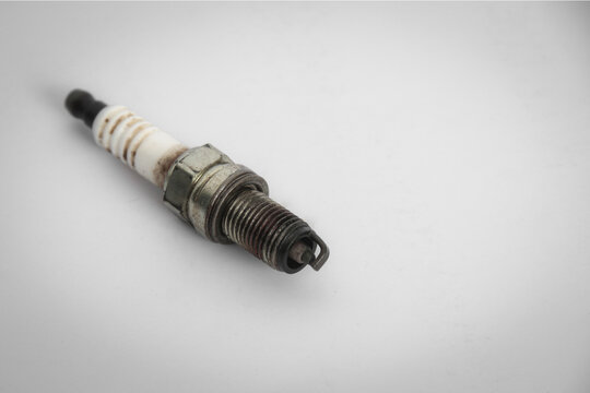 A used spark plug with visible wear and carbon deposits against a clean light background.