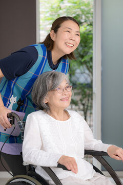 An image of a bright future and hope for senior care filled with peace of mind and smiles, featuring a female care worker supporting an elderly person in a wheelchair, home care, and monitoring servic