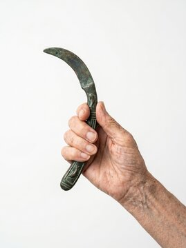 An elderly person holding an ancient bronze sickle tool on a white background.