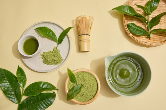 Green tea powder, fresh leaves, brewed tea and bamboo whisk arranged as a natural ingredient scene for tea brands, matcha products, skincare makers and cosmetic packaging designers.