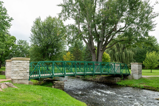 Scenic Green Footbridge Over a Flowing Creek in a Lush Park