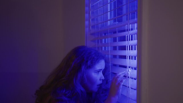 Child fear face in darkness. Kid scared face at night. Child anxiety face near window. Kid afraid indoors. Child frightened face in police lights. Kid panic in darkness.