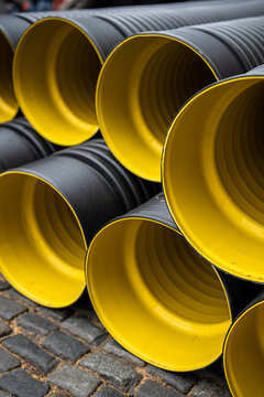 Major maintenance and repairs in urban city, plastic water PVC pipes stacked on ground, bunch of round corrugated tubes ready for installing at construction site, renewal of plumbing systems in town.