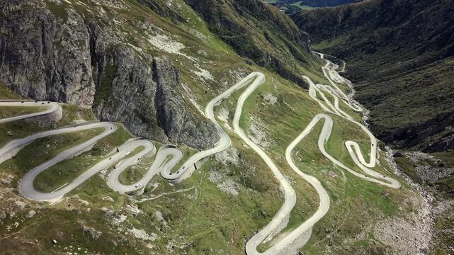 Aerial dolly forward tilt down over Gotthard Pass winding alpine road.