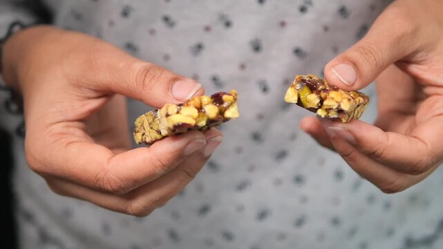 Person Holding a Broken Nut and Fruit Energy Bar