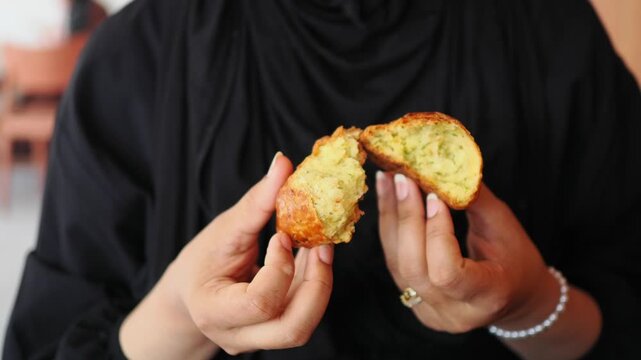 woman breaking a bread roll in her hands at a cafe in the afternoon