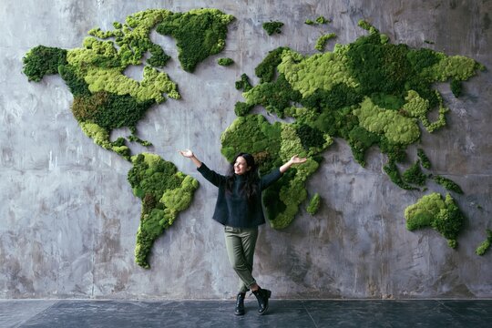 Woman in front of a moss world map on a concrete wall