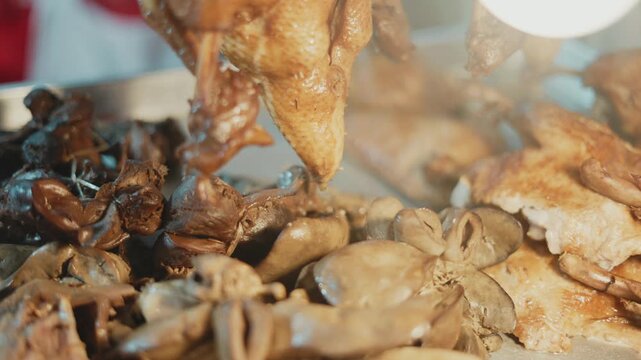 Close up of cooked chicken and giblets steaming at an asian street food stall at night