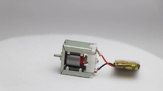 Small dc motor with visible parts in working condition while connected to mini lithium polymer battery