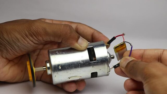 Drill motor or big dc motor with rotating shaft when connected to lithium polymer battery close up view