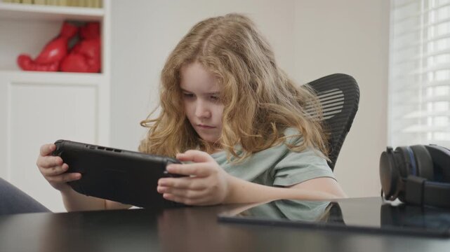 Gaming at home. Kid using a game console. Child gaming online. Gamer concentration on screen. Teenager player gaming console. Kid play game console. Kid playing online computer games.