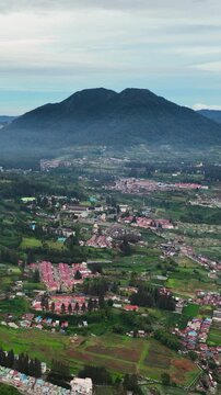 Aerial view of valley with farmland and the town of Berastagi. Sumatra, Indonesia. Vertical video.