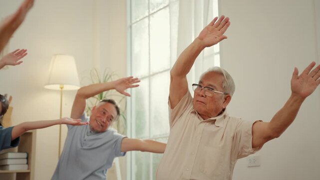 Caregiver senior wellness nursing home exercise class for older adult gentle arm stretching mobility therapy balance support healthy aging lifestyle in bright living room