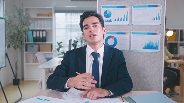 Confident businessman on suit speaking and explaining ideas directly to camera during a video call meeting in office