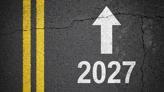 Painted white directional arrow and numbers twenty twenty seven on dark asphalt highway surface top view