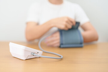 Fototapeta premium woman checking Blood pressure by Blood pressure monitor with Cuff. Systolic, SYS, Diastolic, DIA, Pulse, Hypertension, Hypotension, Heart rate, Cardiovascular Disease and May World hypertension day
