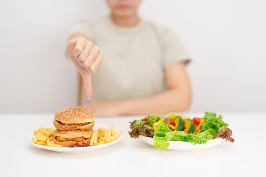 woman with Hamburger and thumbs down, Rejecting and refusing.Healthy and Unhealthy Food Choice, Calories and Nutrition of vegetables Salad and Hamburger. dieting, weight loss, junk food and lifestyle