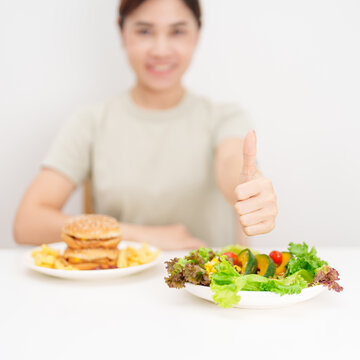 happy woman choose vegetables Salad and thumbs up gesture. Healthy and Unhealthy Food Choice, Calories and Nutrition of vegetables and Hamburger. dieting, weight loss control, junk food and lifestyle