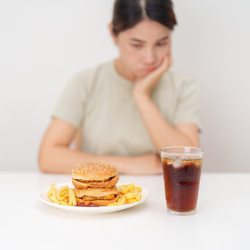 Unhappy woman disgust gesture and Bored to eat Juicy beef burger, potato chips and carbonated Soft drinks. Unhealthy, High calorie, Fast food craving, Obesity, diet, weight loss and junk food