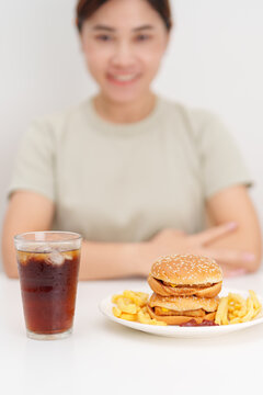 happy woman with Juicy beef burger with melted cheddar cheese, potato chips and carbonated Soft drinks. Unhealthy, High calorie, Fast food craving, Obesity, diet, weight loss, junk food and lifestyle