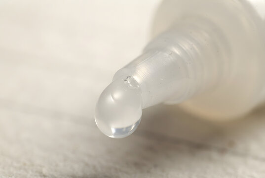 &bull;	Close-up macro view of thick white liquid glue emerging from the nozzle of a squeeze tube