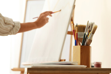 Creative expression and artistic hobby, woman painting on canvas with paintbrush in bright studio workshop for art therapy and personal development © Pixel-Shot