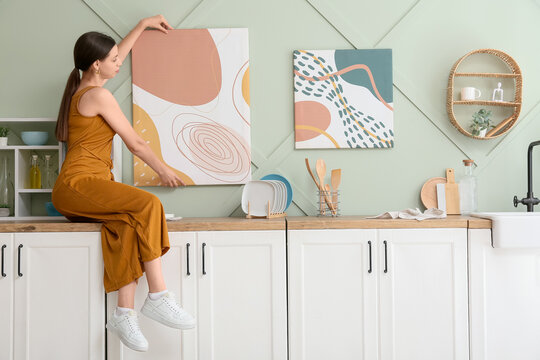 Home improvement and interior design, woman hanging abstract art on kitchen wall to renovate living space and personalize modern house decor